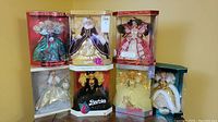 7 Barbie dolls in original boxes showing various holiday-themed costumes and packaging.