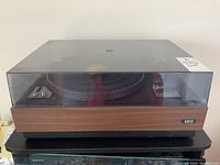 Front view of Keio record player with wooden base and transparent dust cover in place.