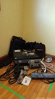 Overall lot contents including HP Officejet 4630 printer, Electrohome alarm clock, Panamax power bar, laptop bag, cameras, cables and other accessories