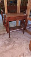 View of the hall table front showing the single drawer and side racks missing front panels, turned legs, and lower shelf.