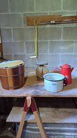 Photo showing the full lot on a wooden table: Frost King wooden ice cream maker on the left, American Family scale in middle back, white enamel kettle in front center-right, red enamel pot on the right.