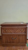 Front view of Kroehler wood veneer nightstand showing two drawers with gold tone knobs and metal pull handle, visible veneer damage.