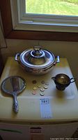 Overview of all items: silverplate chafing dish with lid, silverplate cream dispenser, assortment of coins on table, and vanity mirror.