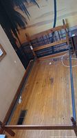 Full view of the wooden single bedframe assembled showing metal rails and wood slats with spindle style posts