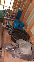 Long view of the lot showing black oil pan, grey fabric car cover, hand tools on a wooden bench in a barn setting.