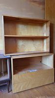 Front view of two wooden shelves stacked, showing the larger shelf with drop-down door bottom and smaller shelf on top.