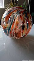 Photo showing the multicolored swirl pattern on the large glass ball with orange, blue, white, and other colors visible.
