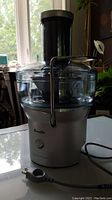 Front angled view showing the full juicer with power cord and clear chute.