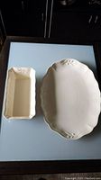 Large oval cream stoneware platter and rectangular serving dish side by side on light blue surface