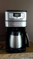 Frontal view of stainless steel and black Cuisinart coffee maker with thermal carafe inserted.