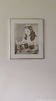 Framed photo of Dorothy reading The Wizard of Oz book on a wall.