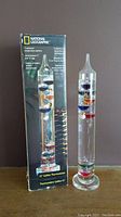 15-inch National Geographic Galileo Thermometer with original box standing side by side on a flat surface