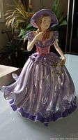 Full view of the Royal Doulton Julia figure in flowing purple dress with hat and bouquet.