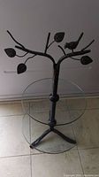 Full photo of two tier glass stand with bird and leaf metal top, showing overall structure and bottom tier glass plate.