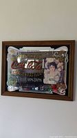 Front view of vintage Coca Cola mirror with visible branding and image of woman holding glass.