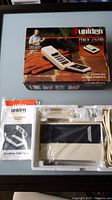 Full view of Uniden Mini-2600 cordless phone in original box with manual and cords, white and black plastic phone shows neatly packed inside foam insert.