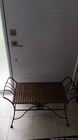 Overhead view of vintage wrought iron bench with rectangular wicker seat.