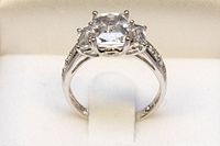 Front view of ring showing emerald-cut center cubic zirconia and side stones