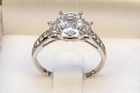 Front view of ring showing cushion-cut center stone and trapezoid side stones.