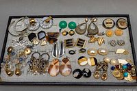 Top-down photo showing most of the earrings laid flat on a felt tray, various styles and colors visible.