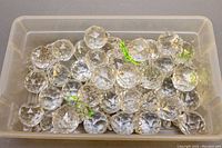 Top-down photo of clear faceted chandelier crystal drops in a plastic bin showing quantity and condition.