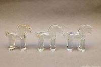 Front and side view of 3 clear blown glass horse paperweights showing their transparent form, block legs, and textured manes