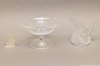 Front view showing all three Waterford crystal pieces on a neutral background: small seahorse figurine, pedestal candy dish, and creamer jug.