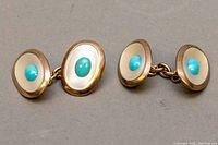 Pair of oval rose gold cufflinks with turquoise stones set in the center, showing front view with polished border and smooth turquoise cabochons.