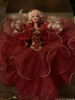 Front view of Happy Holidays 1991 Barbie doll seated in box with red glittery dress expanded.