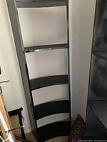 Single view of one black shelving unit showing rounded shelves and black finish
