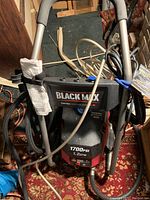 Front view showing Black Max branding, pressure rating, power specifications, attached hose and power cord wrapped around the frame.