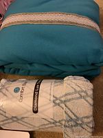 Both blankets folded and stacked: blue fleece blanket on top, Diamond Lux plush blanket below with visible label.