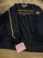Full view of black light jacket with elastic cuffs and a gold stripe down the sleeve, Nashville Predators secondary logo patch on left sleeve