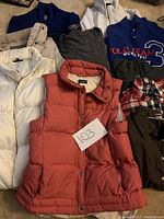Photo showing an assortment of women's tops, vests, and light jackets, various styles and colors laid out together