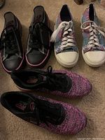 Photo showing three pairs of women's sneakers: black Skechers Air, colorful Roxy, and purple Airwalk sneakers.