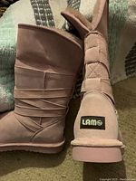 Side profile of two pink LAMO boots showing fleece lining and suede exterior, size 8, with strap detailing and LAMO brand label near heel.