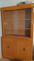 Full front view of vintage wood china cabinet showing upper glass sliding doors and bottom storage doors