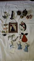 Overview of assortment including ceramic angels, metal pitchers, bird figurines, decorative plaque, and ceramic pear.