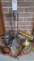 Overview of the lot showing brass lamp, fire tools, coffee grinder, and bellows on floor against brick wall.