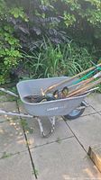 Front view of gray plastic Uberhaus wheelbarrow containing assorted hand tools