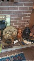 Overview of lot on hearth against brick wall: lantern, irons, planes, brass plaque, wooden bust, duck decoy and binoculars