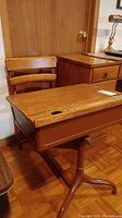 Side view of the vintage wood school desk with attached swivel chair showing the wooden seat, backrest, and desk top with a hole for inkwell.