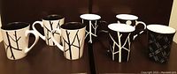Group photo of six black and white patterned stoneware coffee/tea cups arranged on dark surface.