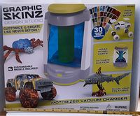 Front view of box showing motorized vacuum chamber and customizable models including truck, spider, shark, and graphic skin transfers included.
