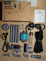 Complete set of Hygger electric gravel vacuum cleaner components laid out on floor, showing motor unit, extension tubes, various nozzle attachments, black hose, power cords, clear plastic chambers, user manual, and original box.