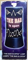 Front view of the boxed lamp showing the "THE BAR is open" illuminated text and decorative lightbolt and wave graphics.