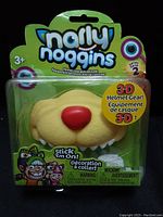 Front view of the Narly Noggins porcupine face 3-D helmet accessory in original sealed packaging showing the red nose and beige textured face.
