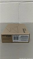 Photo of Netgear ProSafe SFP module in sealed original cardboard box showing product label with model AFM735-10000S and barcode.