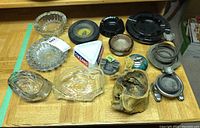Overview photo of all ashtrays and lighter laid out on table showing variety in materials and styles