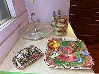 Overview of all items on table including glass serving dish, ceramic floral butter dish, colorful 10x10 plate with server, and Japanese ceramic containers.
